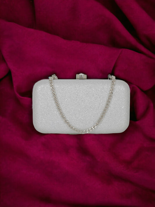 An elegant Vdesi Base silver clutch on a pink fabric.