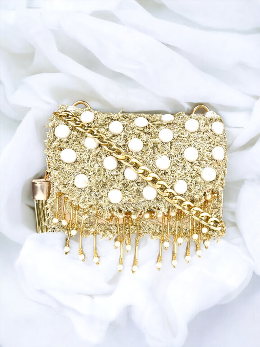 A gold Vdesi sling bag on a white sheet. 