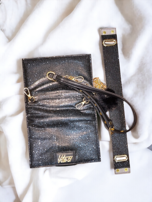A black shiny flip bag with adjustable belt on a plain white background. 