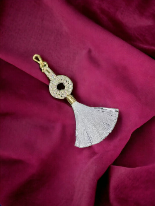 A Vdesi White tassel charm on a plain red sheet. 