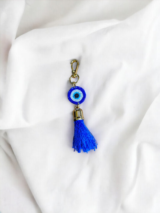 The Evil Eye Tassel Bag Charm is an enchanting accessory designed to ward off negativity and bring a touch of mystical allure to your belongings.