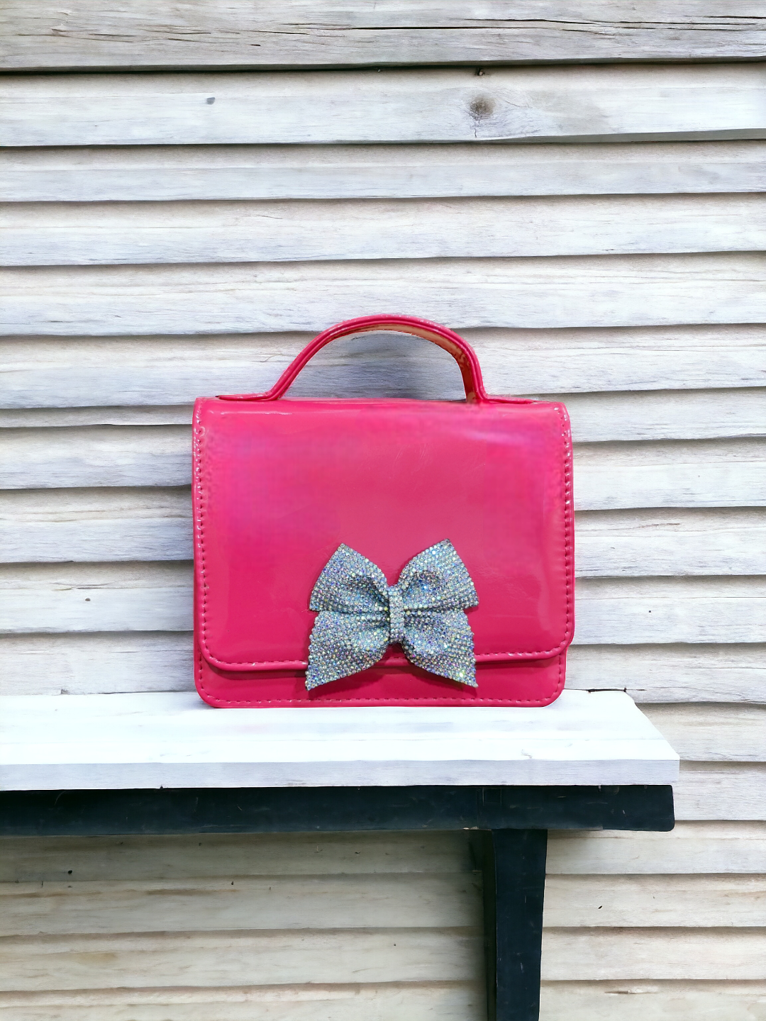 A Vdesi pink handbag with a bow on it. 