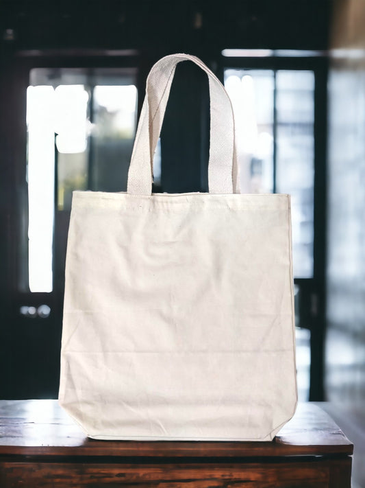 A Vdesi white tote bag on a plain brown surface. 